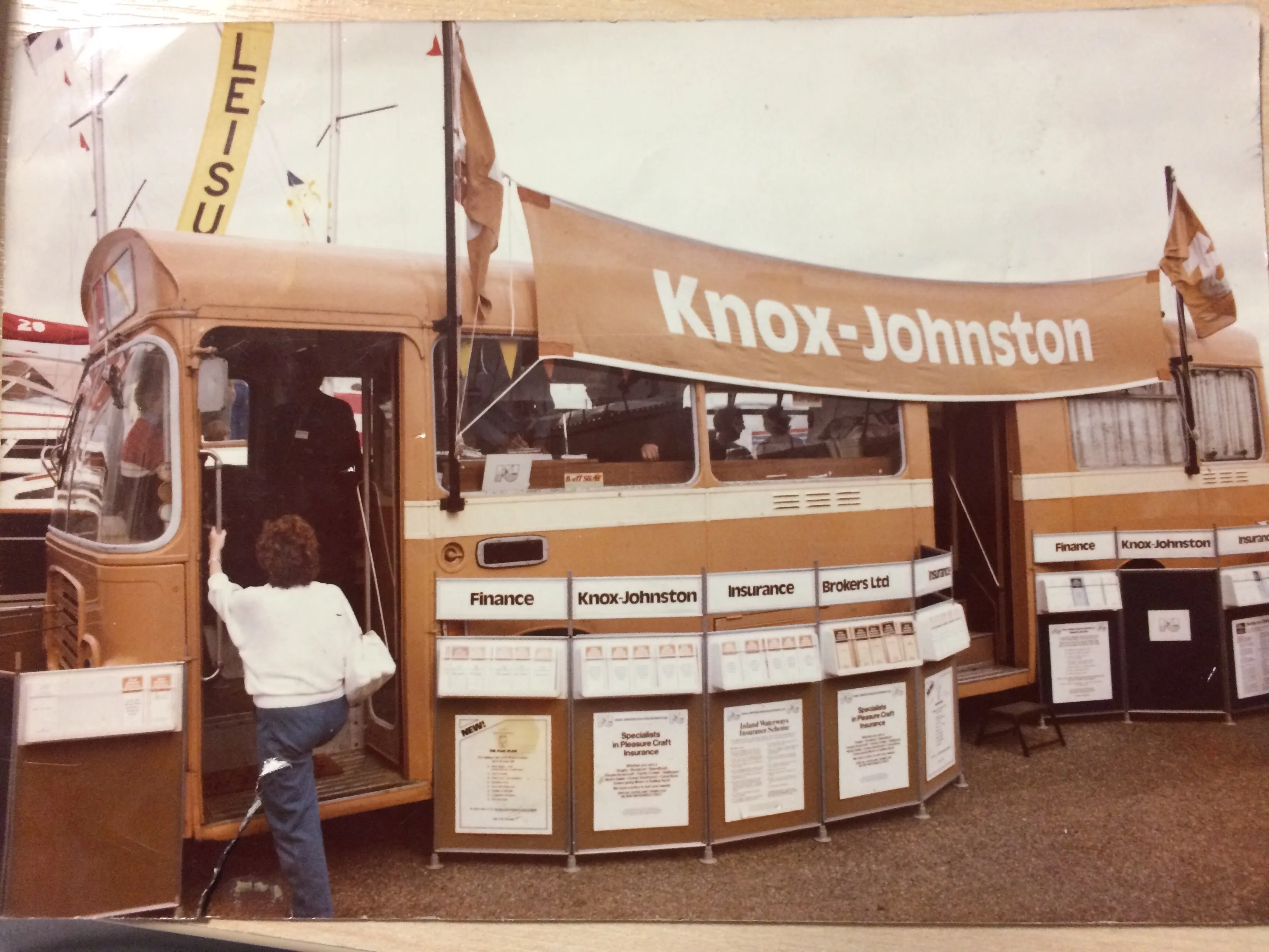 Person entering a Knox-Johnston branded bus with finance and insurance service displays outside.